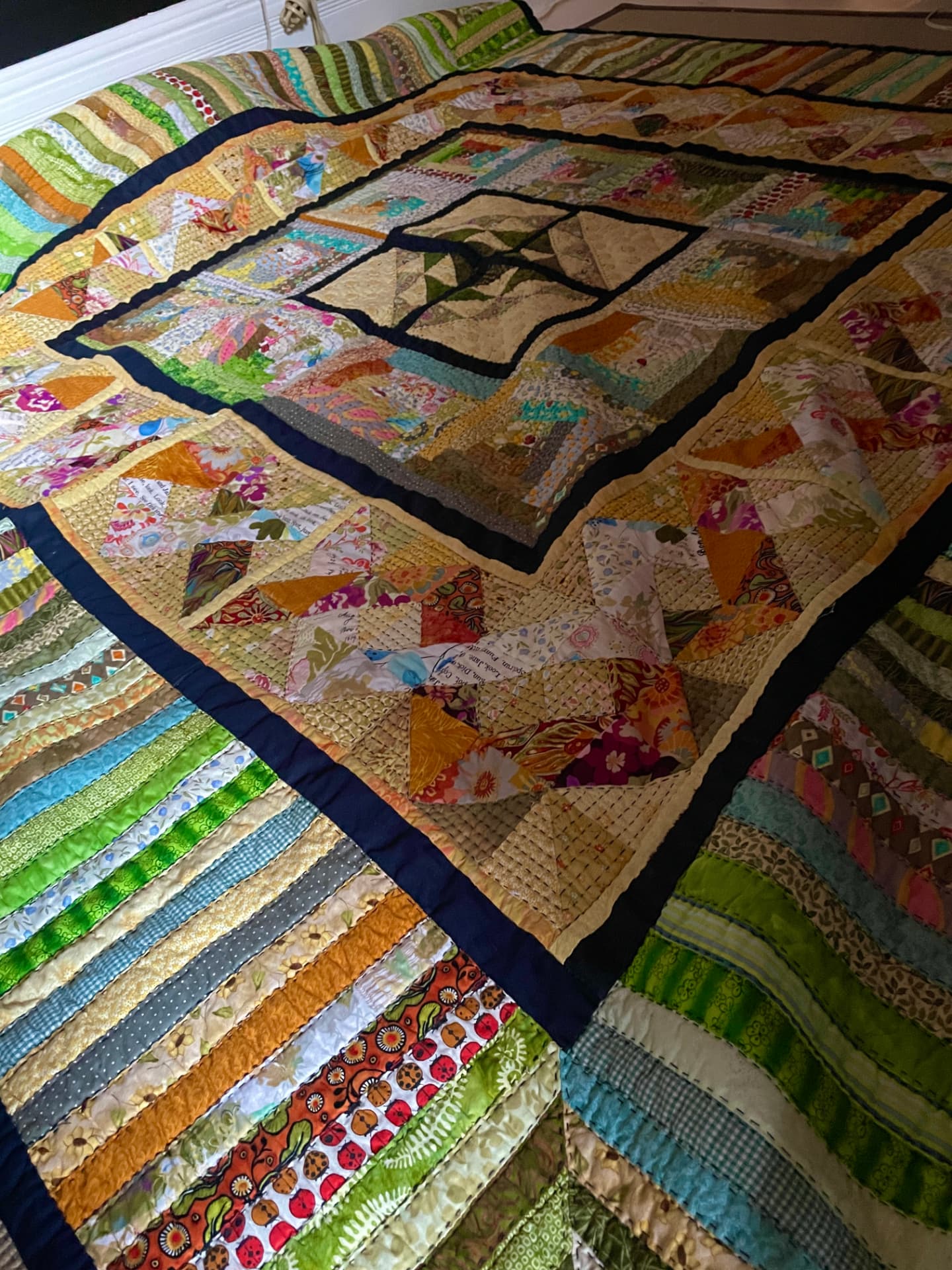 Brandon's C$24,000 story quilt: strip-pieced borders around scrappy blocks, hand-quilted in quarter-inch big-stitch rows